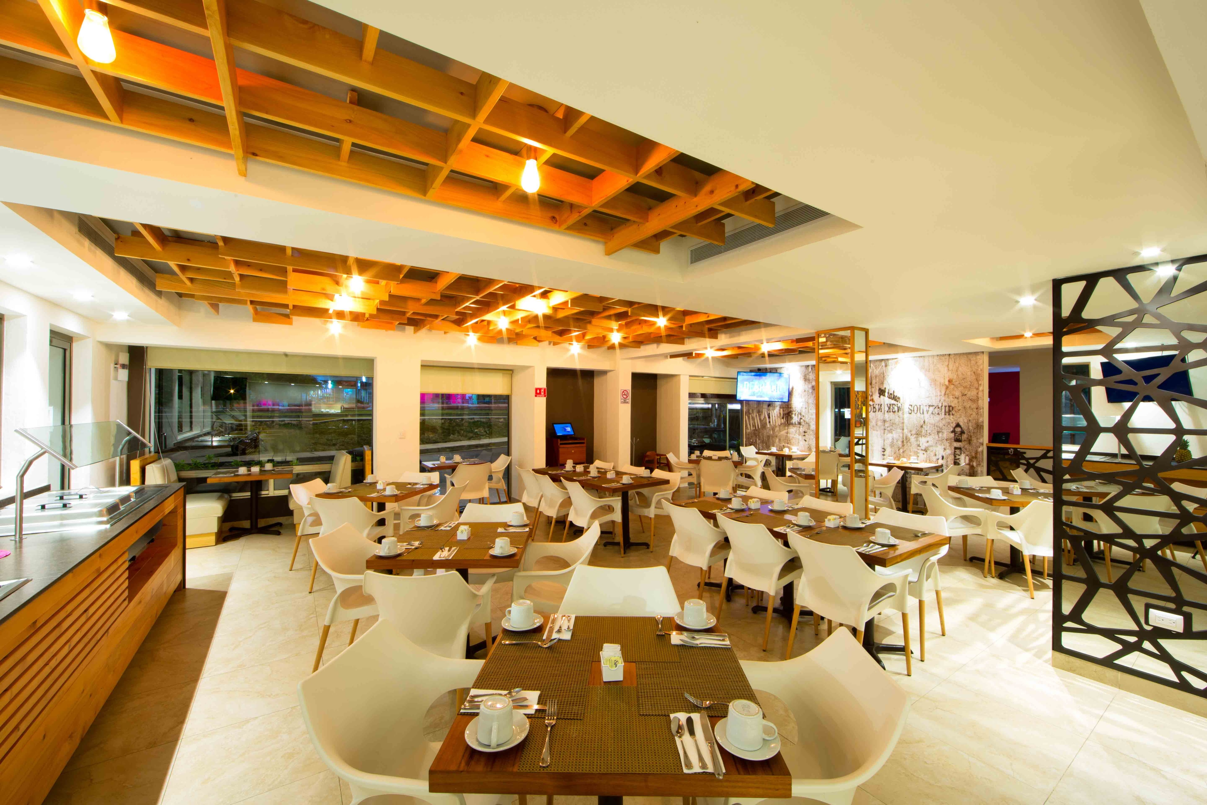Restaurant dining room with wood-beam ceiling and modern décor at Ambiance Suites