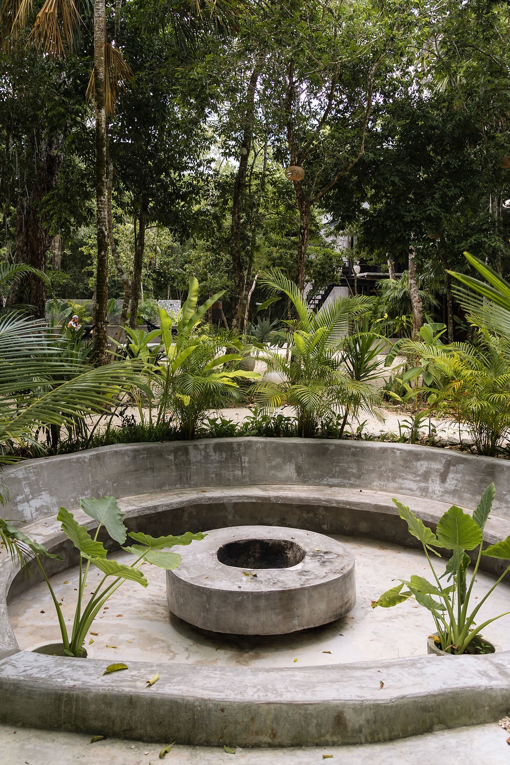 Circular concrete fire pit surrounded by tropical garden at Casa Tattva
