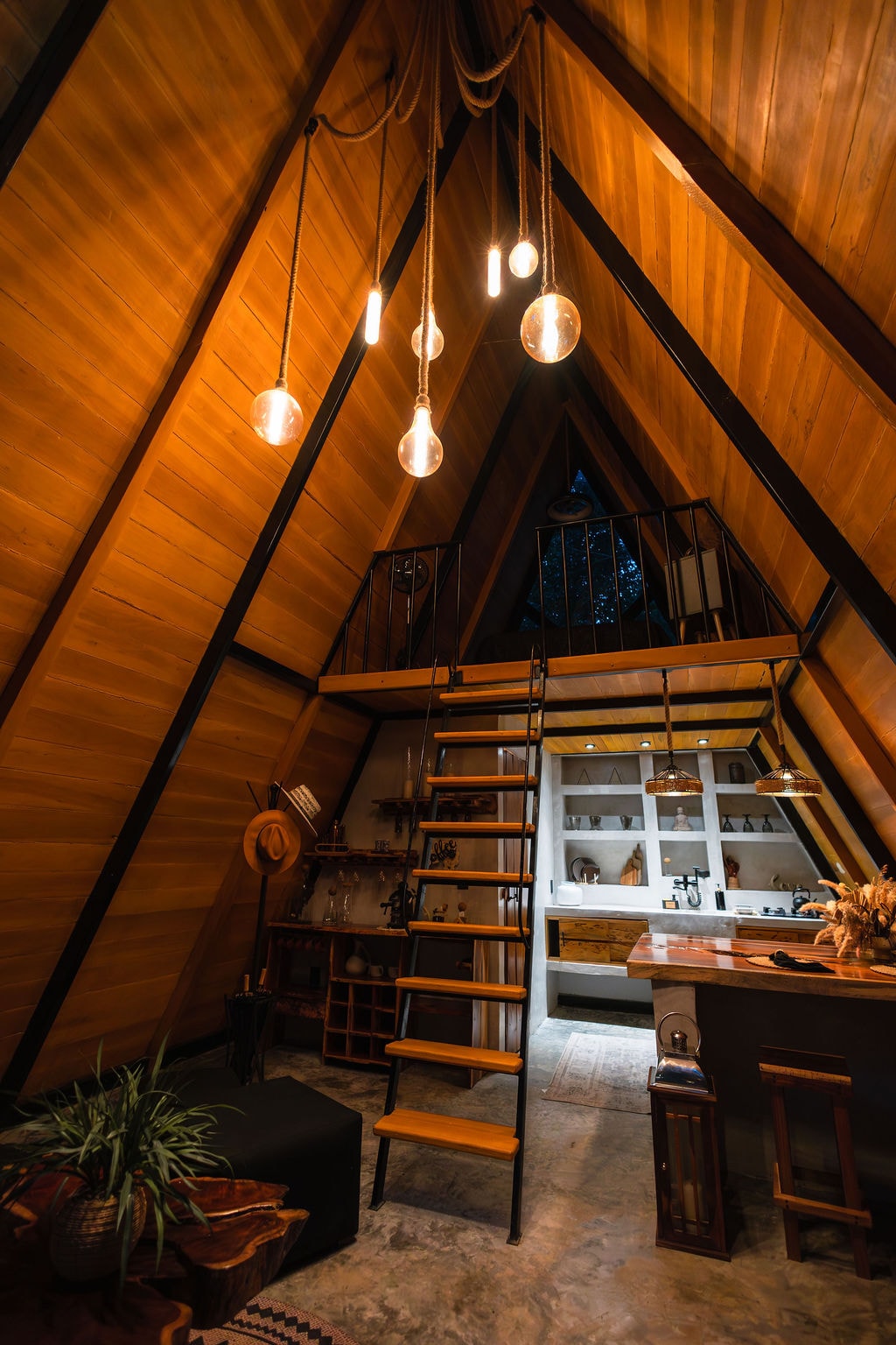 A-frame cabin interior with loft, pendant lights and kitchen at Casa Tattva