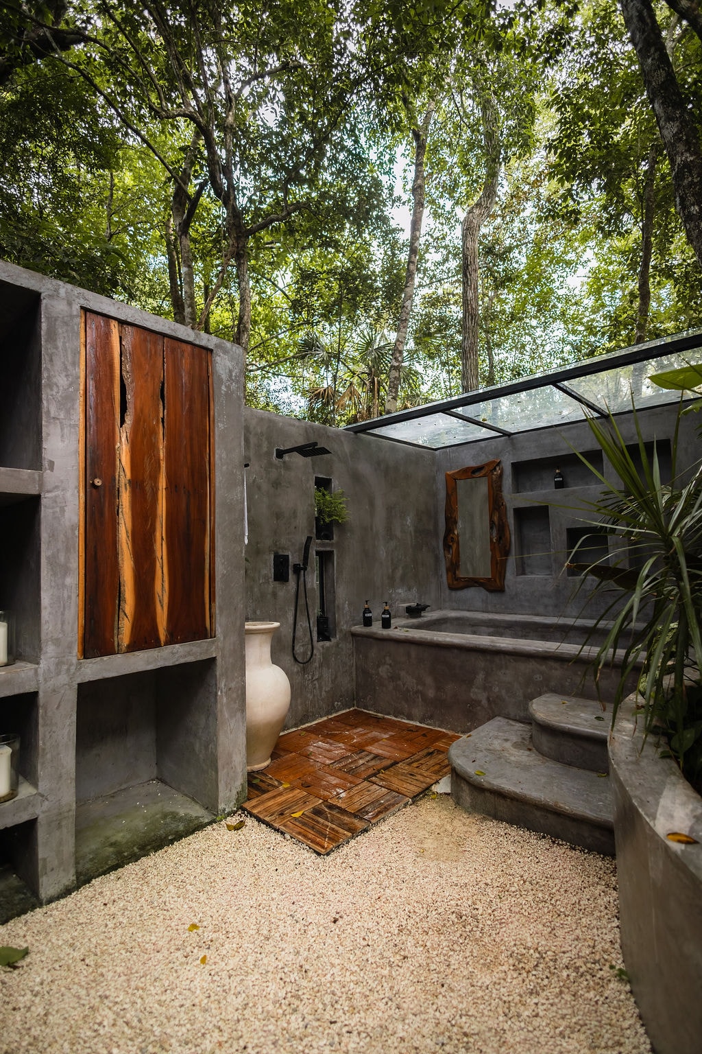 Open-air concrete bathroom with outdoor shower and jungle canopy at Casa Tattva