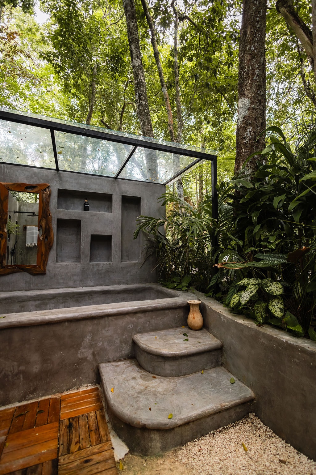 Outdoor concrete soaking tub with glass roof and jungle surroundings at Casa Tattva