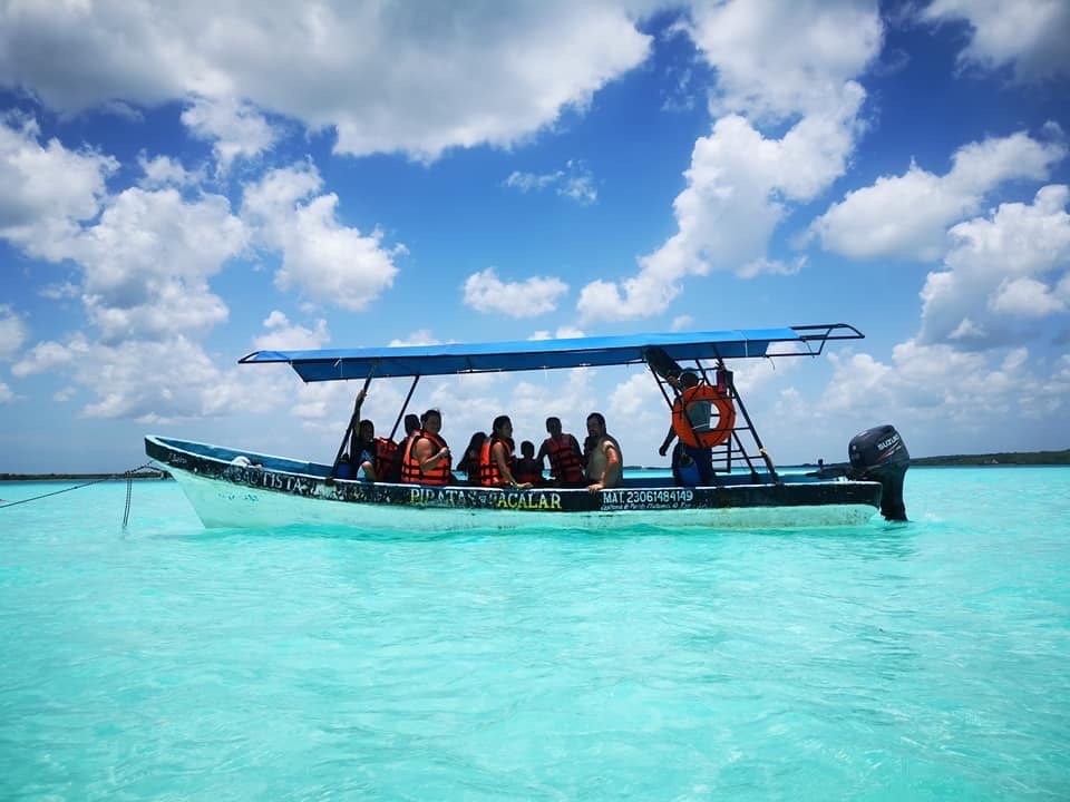 Tour boat with passengers in life jackets cruising the turquoise waters of Bacalar
