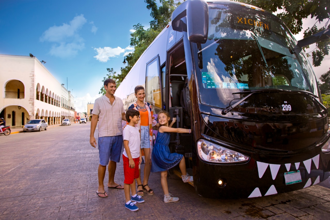 Happy family of four boarding the Xichen luxury tour bus in Valladolid, Mexico