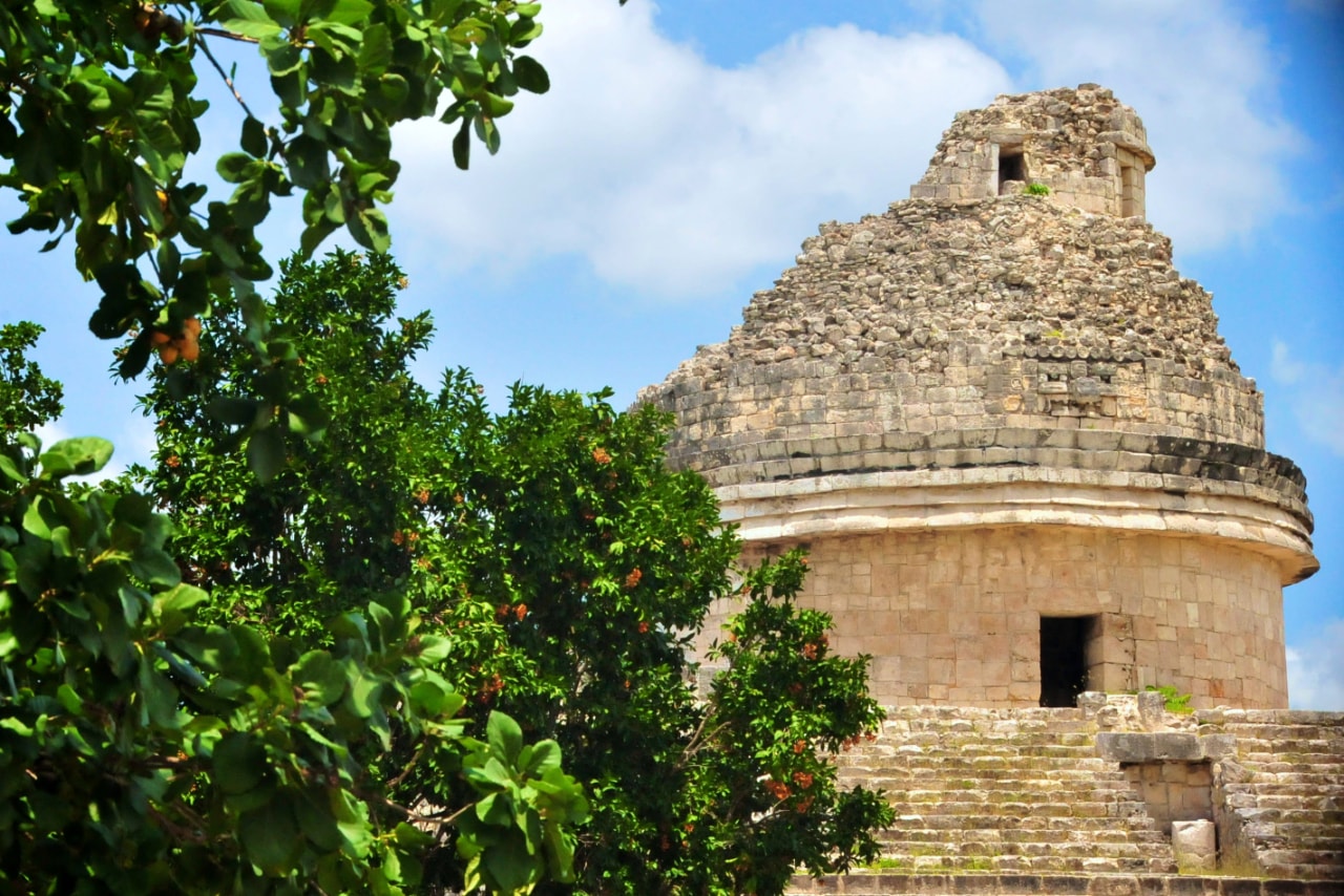El Caracol Mayan observatory tower framed by lush green trees at Chichen Itza